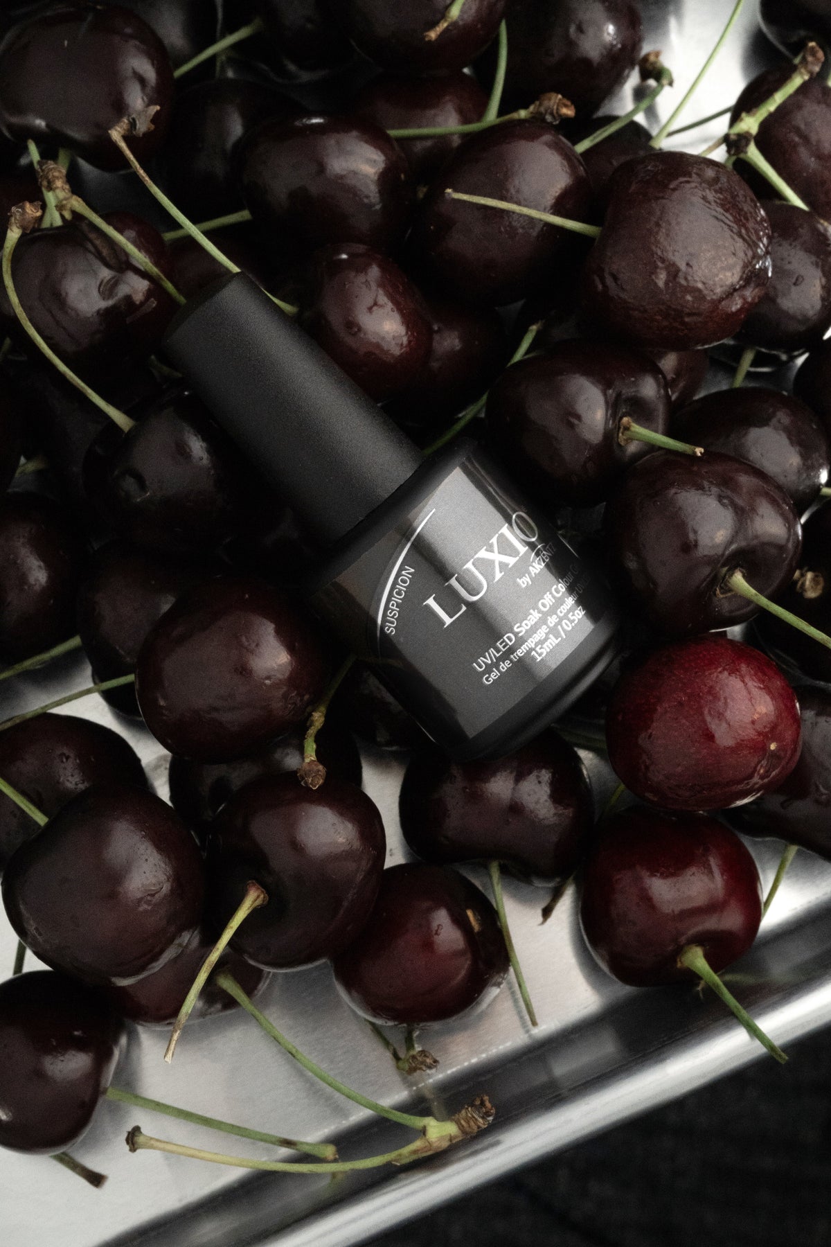 Akzentz Luxio Suspicion gel bottle among dark cherries