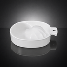 A white ceramic citrus juicer bowl with a handle, shown on a reflective dark gray surface against a black gradient background.