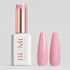 A bottle of BE-MI Beauty Box gel nail polish with a metallic rose gold cap and a white base, shown next to two glossy pink nail tips on a light gray background.