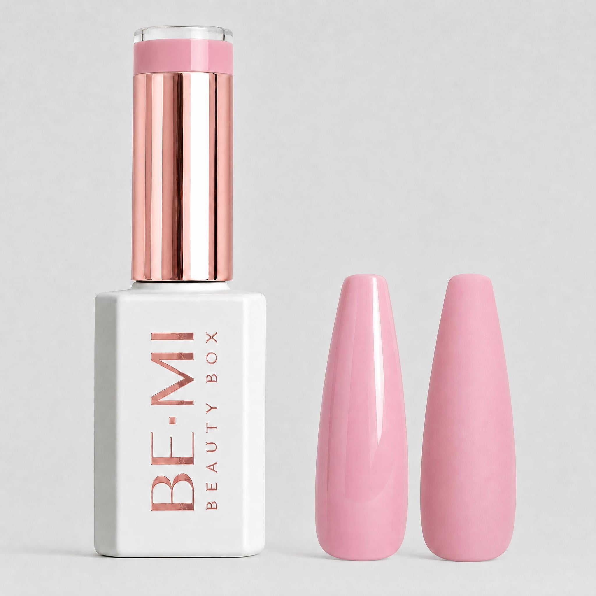 A bottle of BE-MI Beauty Box gel nail polish with a metallic rose gold cap and a white base, shown next to two glossy pink nail tips on a light gray background.