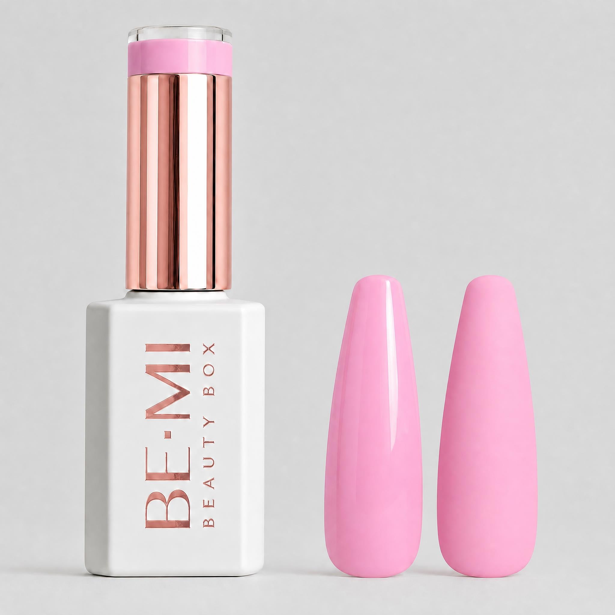 A bottle of BE-MI Beauty Box gel nail polish in a bright pink shade, shown next to two artificial nail tips painted in the same pink color, on a light gray background.
