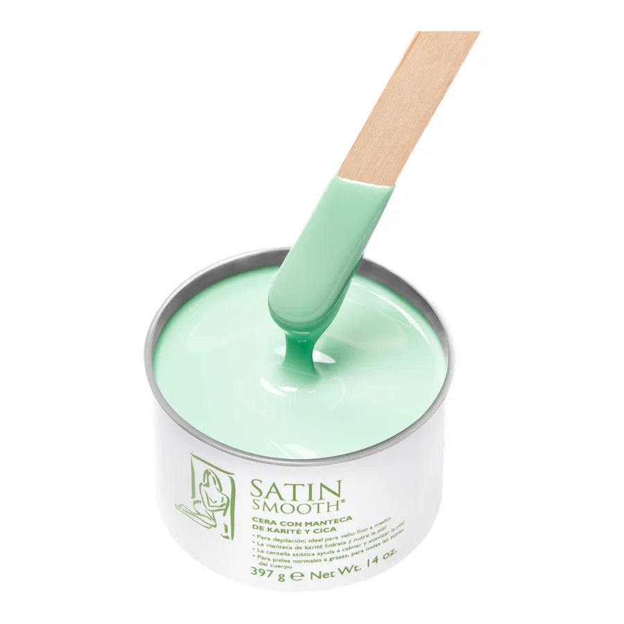A metal tin of Satin Smooth hair wax in a mint green color, with a wooden spatula coated in the wax resting inside the tin on a white background.