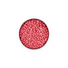 Pink round candies in a metal container on a white background