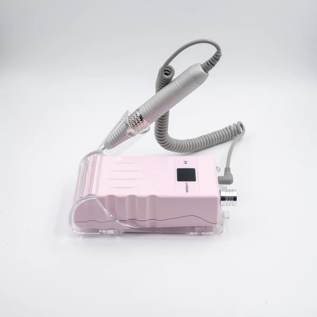 A pink electronic nail drill machine with a clear protective case, a gray coiled cord, and a gray handheld drill bit wand, shown on a white background.