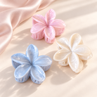 Coconoir Beauty flower hair claw clips in blue, white, and pink on an ivory surface with blush satin.