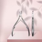 Staleks Classic 12 cuticle nippers with 5mm half jaw, full and side views on a pale pink background