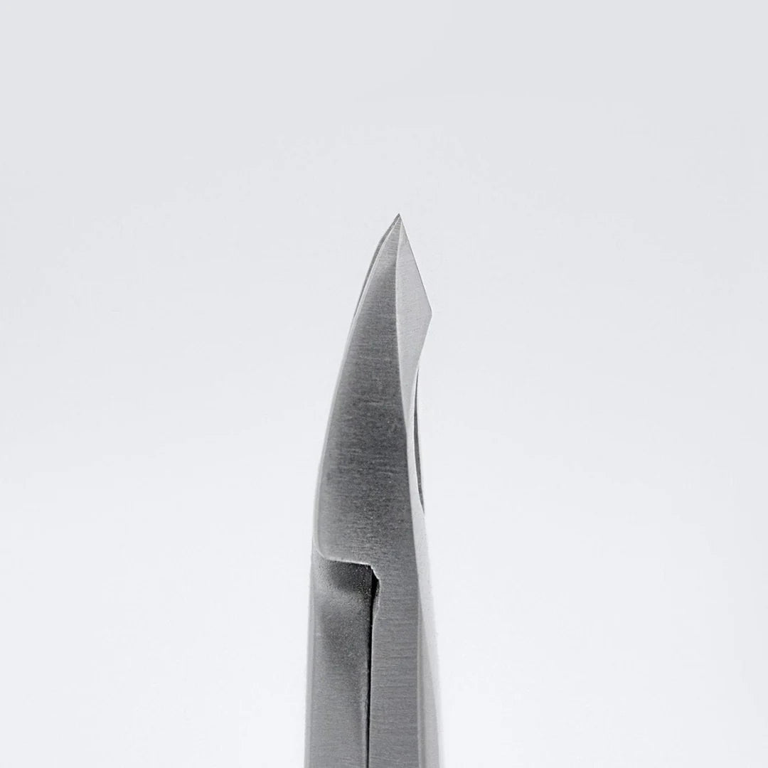 Close-up of a metallic surgical instrument tip, likely a biopsy forceps or similar medical tool, shown vertically against a clean light gray background.